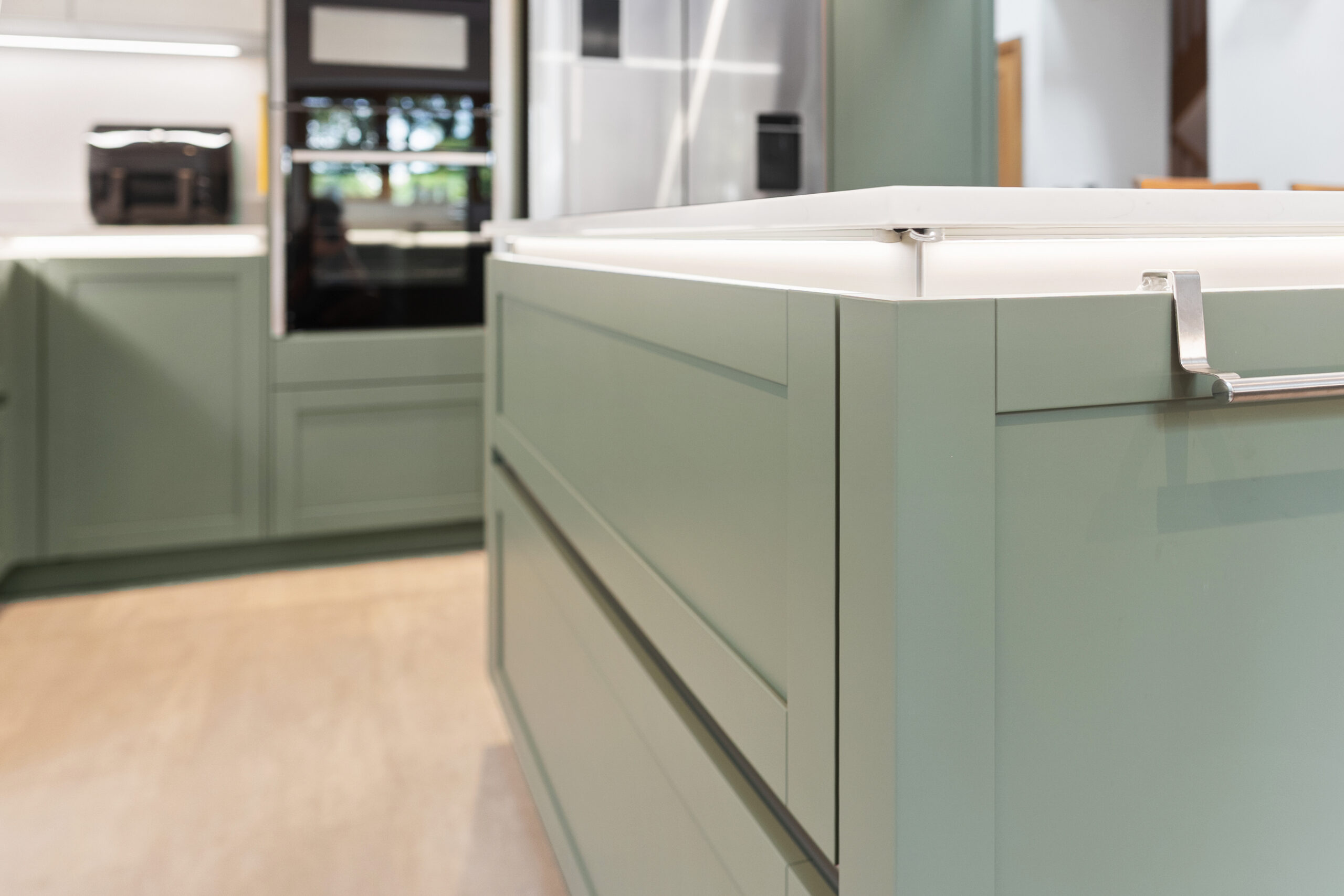Sage green handleless kitchen with island and white quartz worktops