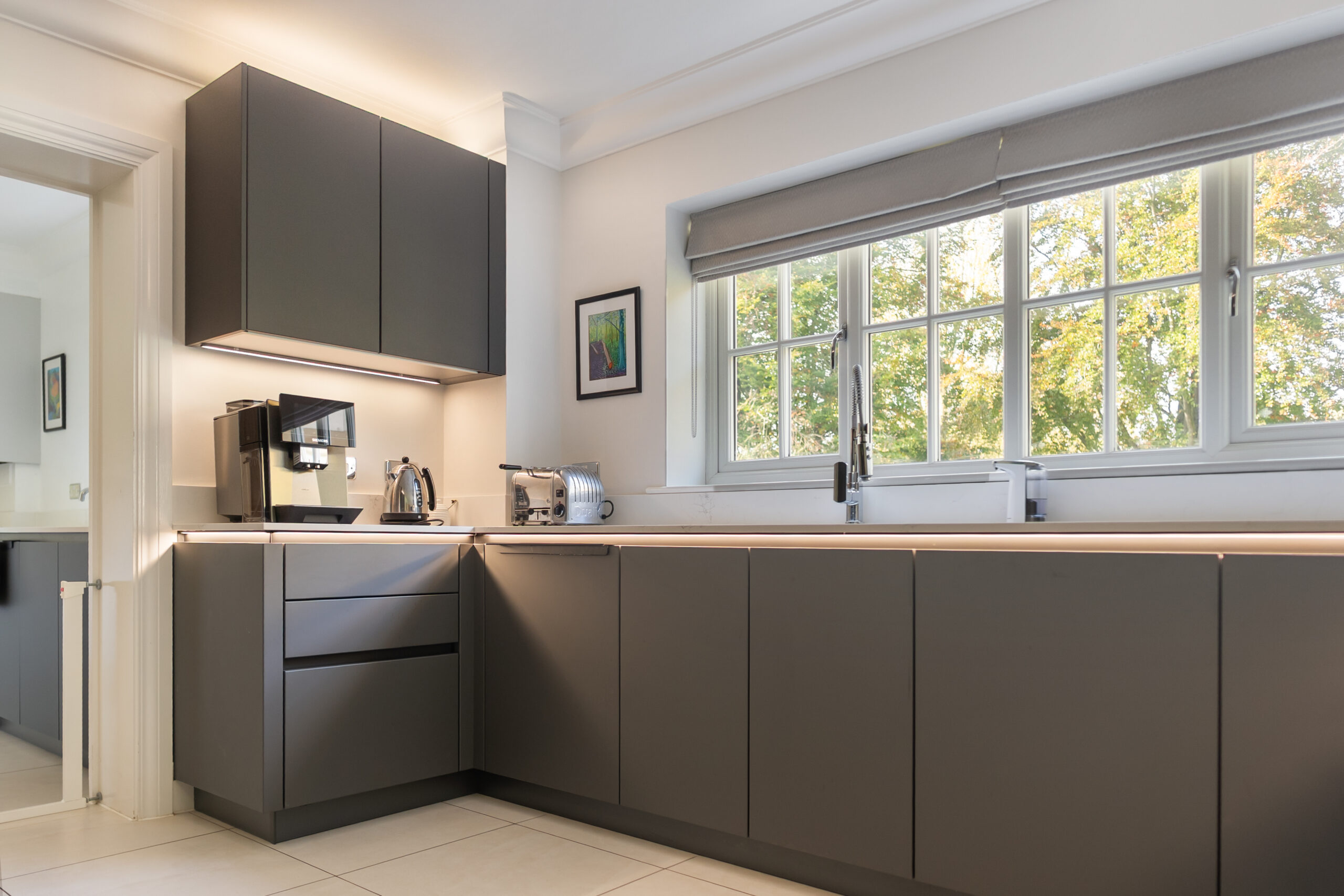Dark grey handleless kitchen with white quartz worktops, fitted by KitchenSMART