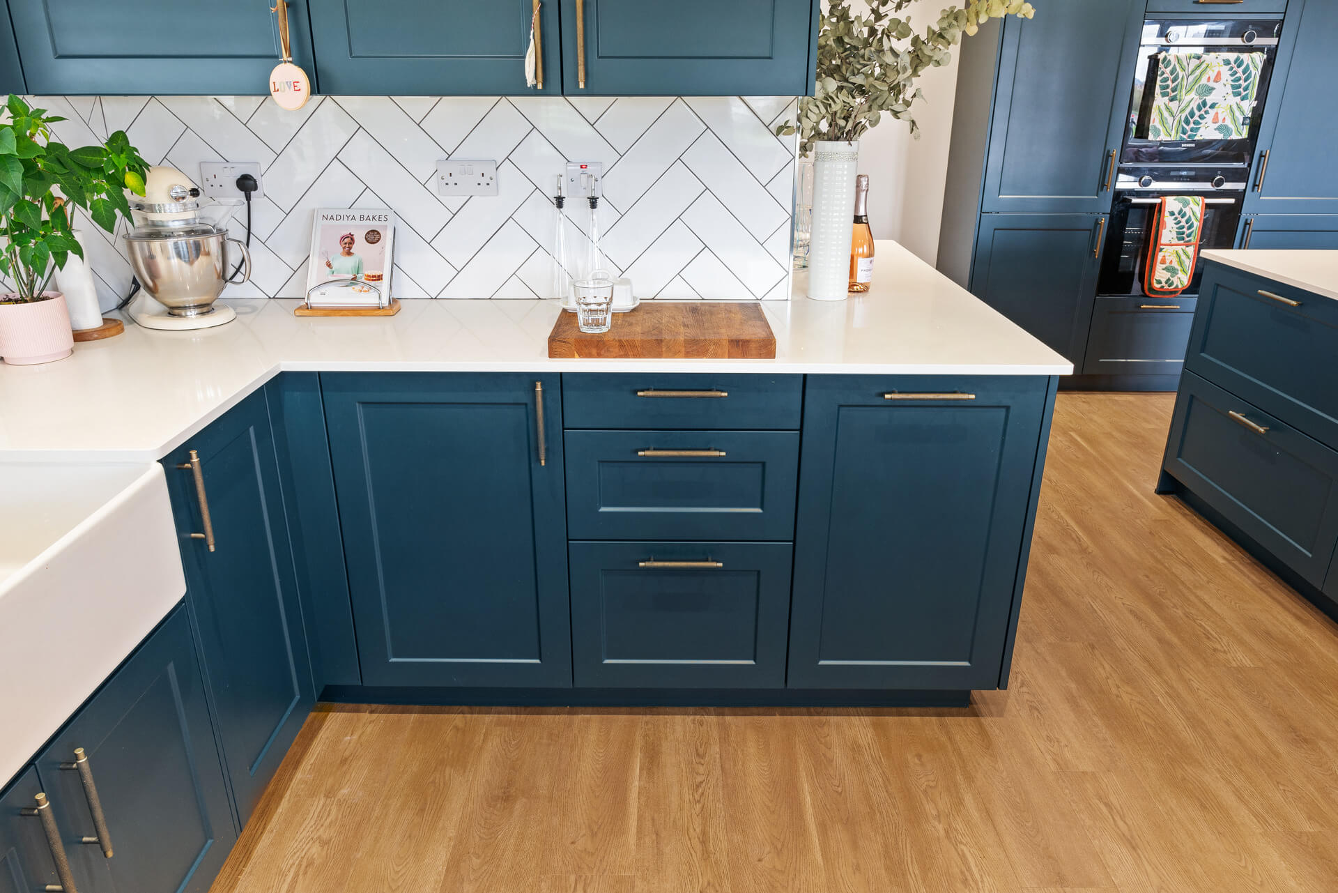 Navy Shaker kitchen with white herringbone tile splashback, Belfast sink and oak floor