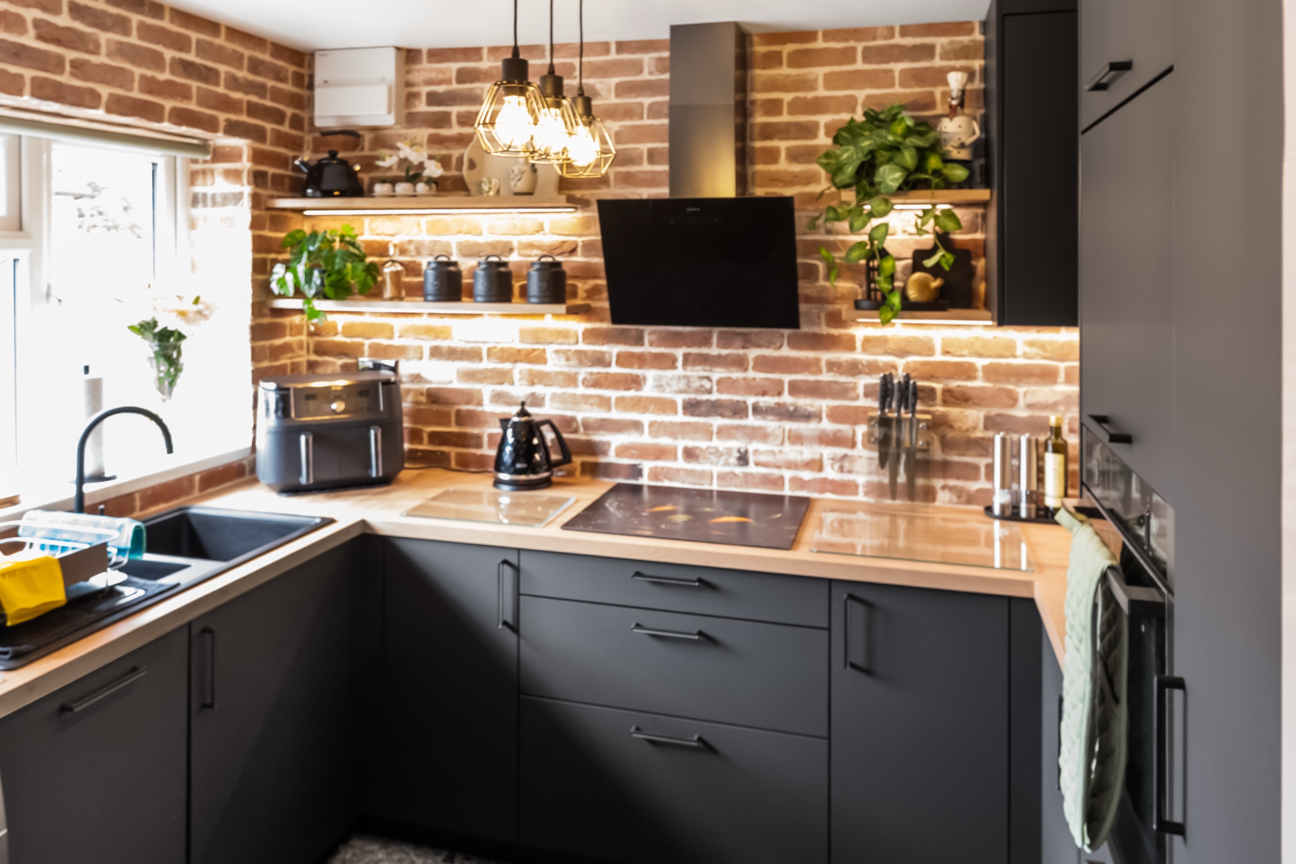 Matera kitchen in Lava Black with a brick splashback and wood worktop